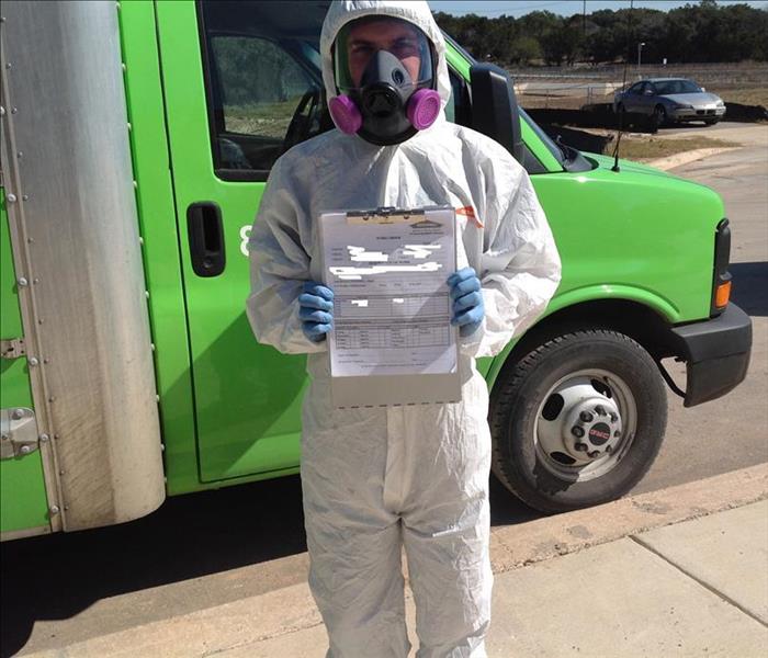 Man in hazmat suit holding up a mold certification